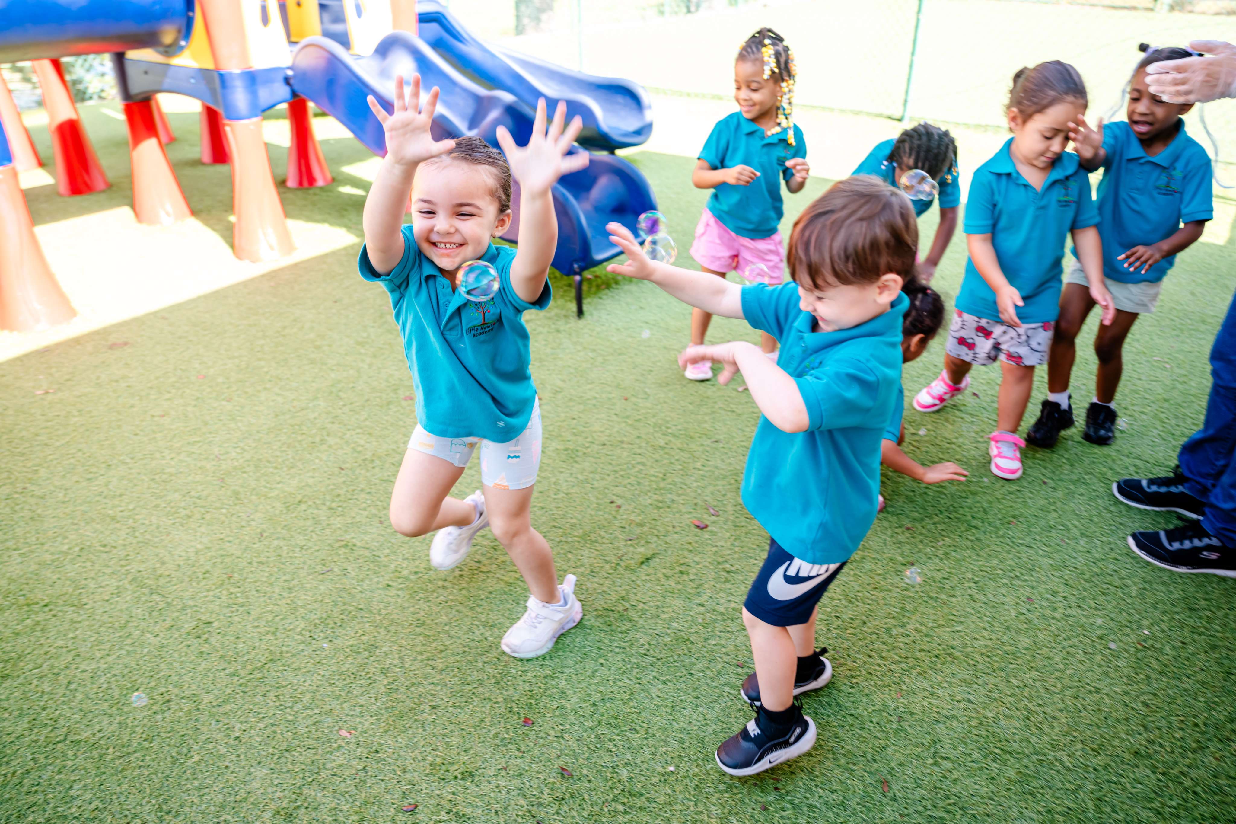 Children joyfully chasing bubbles outdoors at Little Newtons Academy