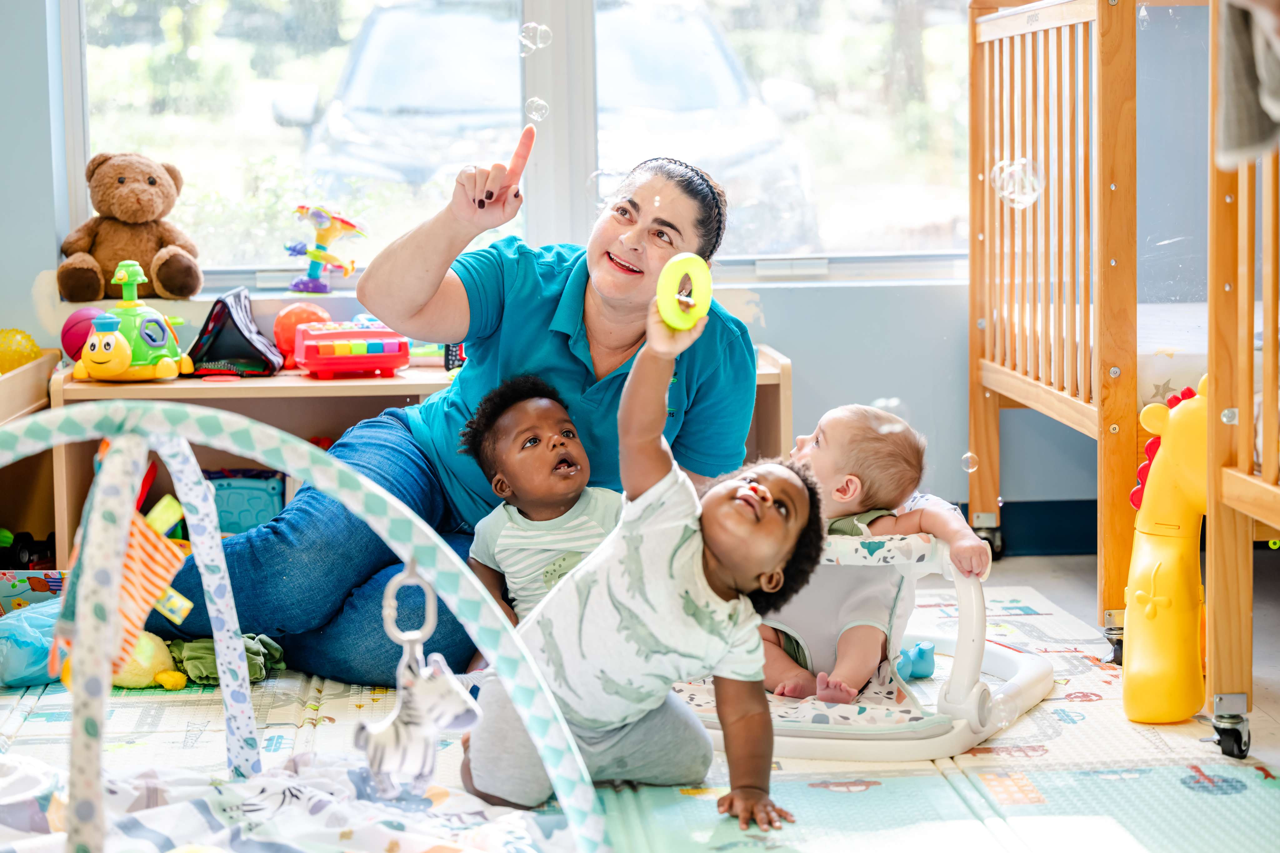 Teacher engaging infants during floor play in the Little Newtons infant room