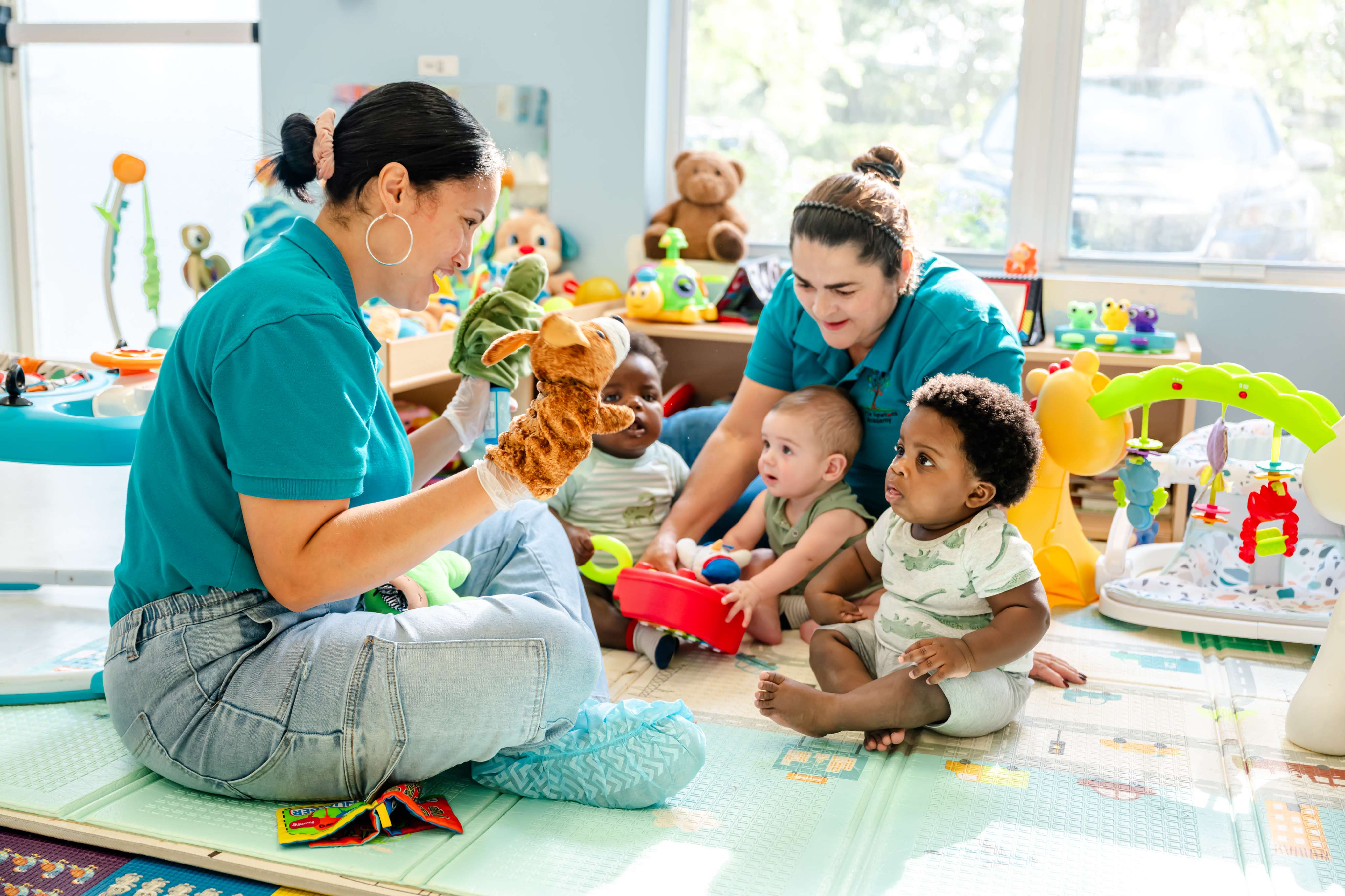 Teachers engaging infants with a puppet during floor play in the nursery at Little Newtons Academy